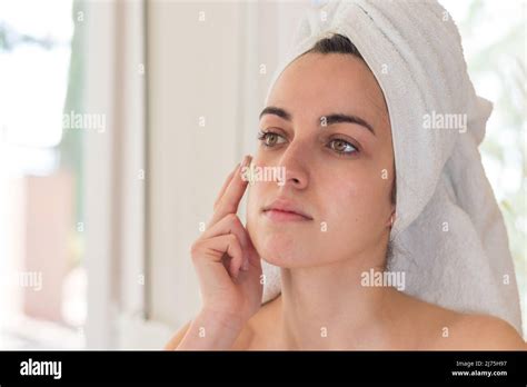 Young Beautiful Girl After Showering With Towel On Head In Bathroom Doing Facial Treatment Skin