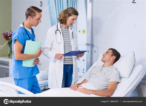 Doctors Talking To Patient In Hospital Bed Stock Photo By
