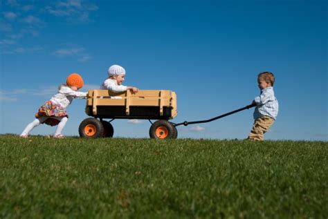 Three Children Pushing Pulling And Playing With Wagon Stock Photo