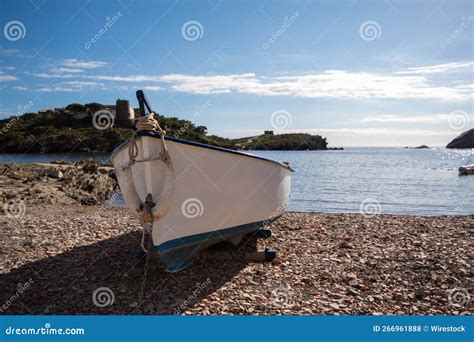 White And Blue Boat Parked On The Stones Of One Of The Small Beaches Of The Catalan Town Of