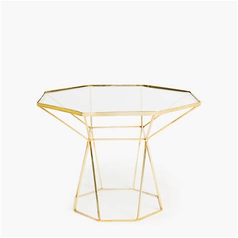 A Glass Table With Gold Metal Legs And A Geometric Design On The Top Against A White Background