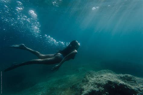 wide shot of a woman swimming underwater by stocksy contributor boris jovanovic stocksy