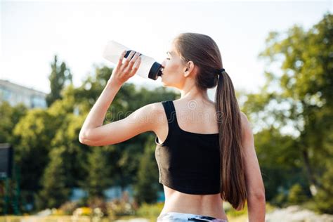Female Athlete Drinking From Water Bottle After Workout At Stadium