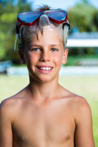 Portrait Of Happy Shirtless Boy Wearing Swimming Goggles At Poolside