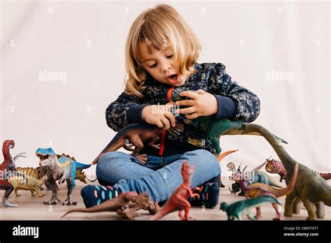 Retrato De Una Niña Sentada En El Suelo Jugando Con Los Dinosaurios De Juguete Fotografía De