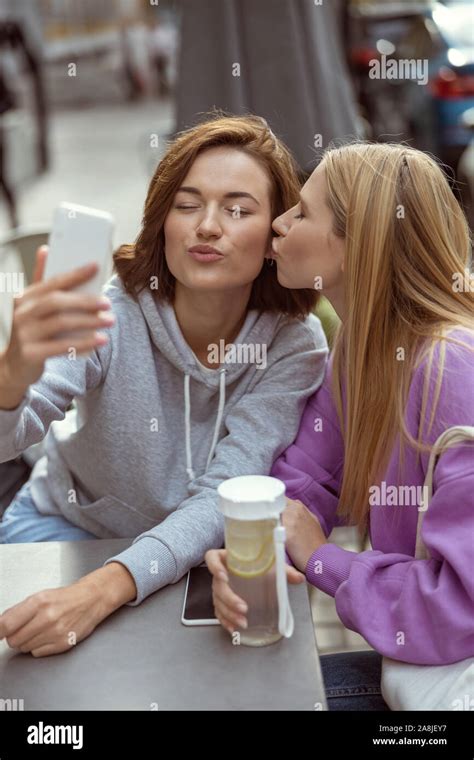 Pleased Longhaired Girl Kissing Her Best Friend Stock Photo Alamy