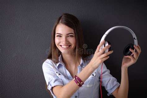 Muchacha Sonriente Con Los Auriculares Que Se Sientan En El Piso Foto