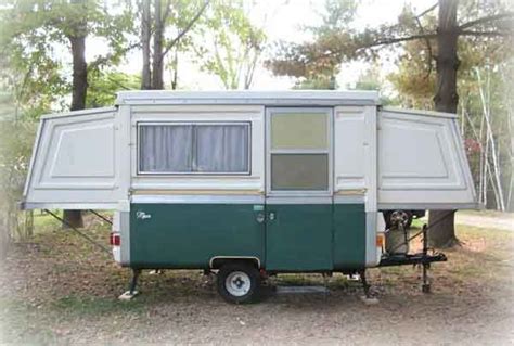 A Small Green And White Trailer Parked In The Woods
