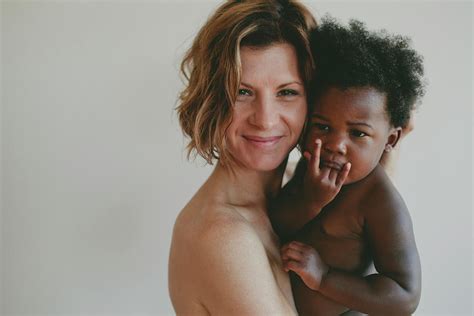 Portrait Of Naked Mother Carrying Daughter While Standing Against White
