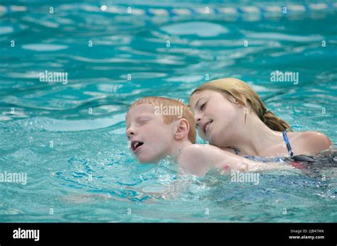 Brother And Older Sister In Pool Playing In Water As She Teaches Him