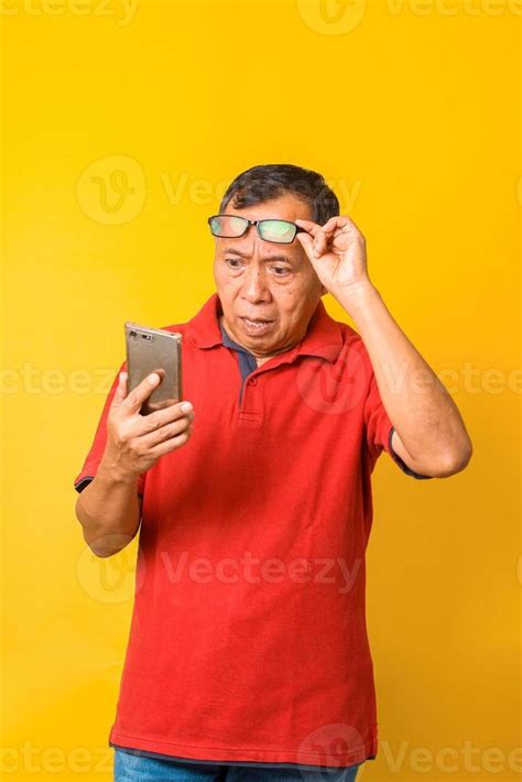 Portrait Of Confused Asian Old Man Looking On Smartphone While Putting