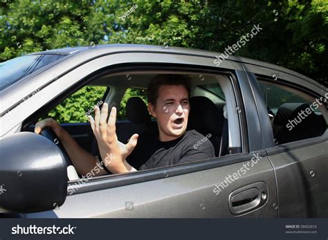 Angry Young Male Driver Yelling And Gesturing To Someone Stock Photo
