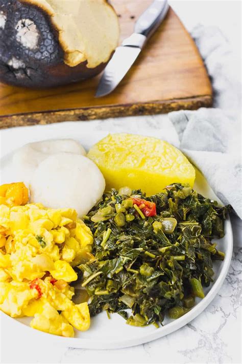 Jamaican Callaloo On White Plate With Ackee Yellow Yam Dumplings And Roast Bread Fruit
