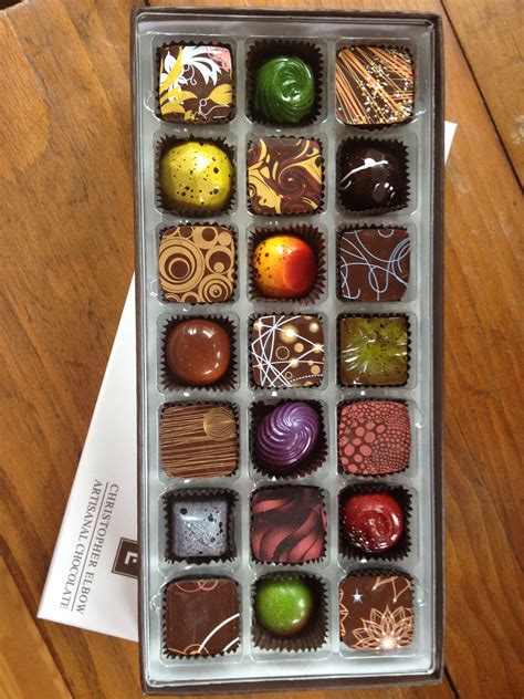 An Open Box Of Chocolates Sitting On Top Of A Wooden Table