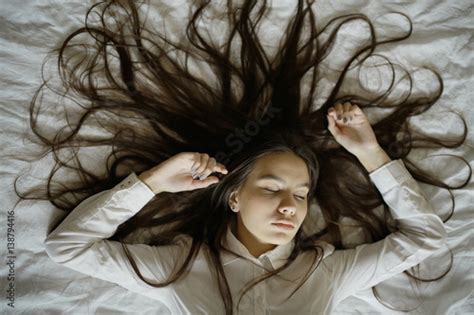 Brunette Beautiful Young Adult With Long Hair Lying On The Bed