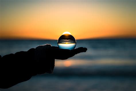 Crystal Ball On Persons Hand During Yellow Sunset Hd Wallpaper