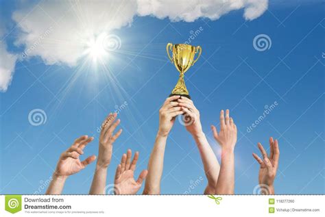 Winning Team Is Holding Trophy In Hands. Many Hands Against Blue Sky ...