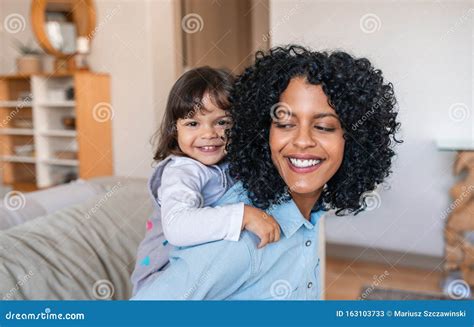 mamá sonriente apoyando a su adorable hija por toda la casa imagen de archivo imagen de