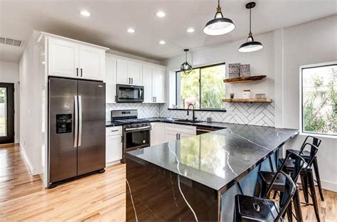 The white cabinets in this kitchen are really taking advantage of black hardware, and black granite countertops. White Kitchen Cabinets with Dark Countertops - Designing Idea