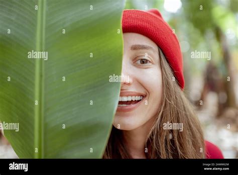 Facial Portrait Of A Cute Smiling Woman Hiding Behind A Banana Leaf On The Plantation