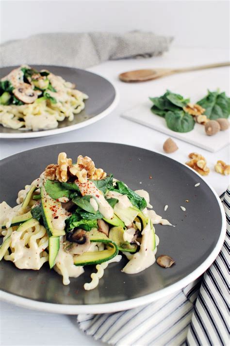 Two Plates Filled With Pasta And Veggies On Top Of A White Table Cloth