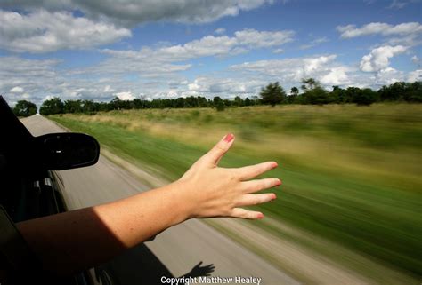 Young Woman With Hand Out Car Window On Road Trip Matthew Healey