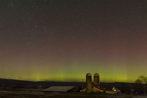 The Northern Lights Shine Behind A Barn And Silos In Pine Bush New