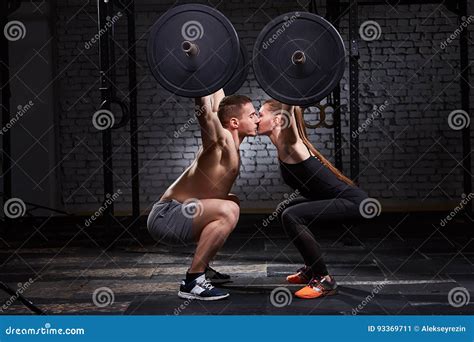 Mujer Joven Y Hombre Juguetones Hermosos Que Besan Y Que Levantan Una Pesa De Gimnasia De