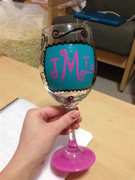 A Person Holding A Wine Glass With The Word M Painted On It In Pink