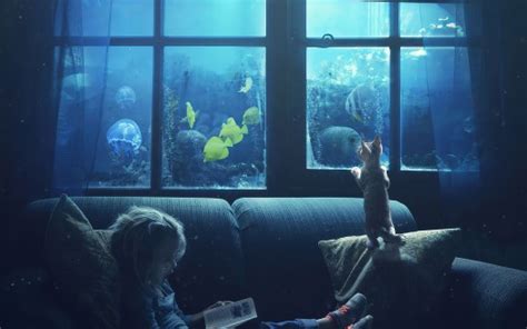Cute Little Girl Is Reading Book And Cat Watching Fishes