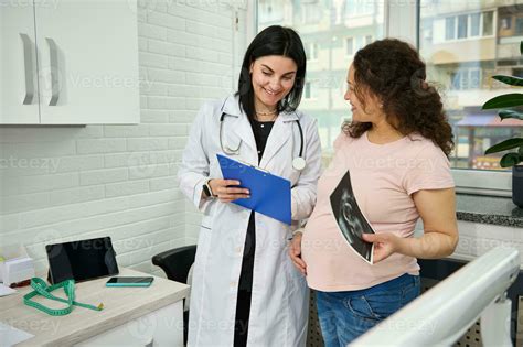 Smiling Pregnant Woman Visiting Doctor Gynecologist Obstetrician In Gynecological Clinic During