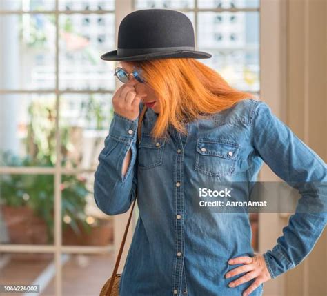 Stylish Redhead Woman Wearing Bowler Hat And Sunglasses Tired Rubbing