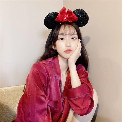a woman sitting on a couch wearing a minnie mouse ears headband with her hand under her chin