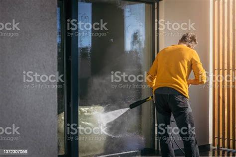 Man Using A High Pressure Squirt Gun To Clean The Entrance Window Of