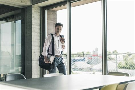Businessman Standing By Window Entering The Office Stock Photo