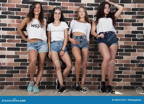 quatre jeunes filles dans les shorts blancs de t shirts et de jeans tenant le nea image stock
