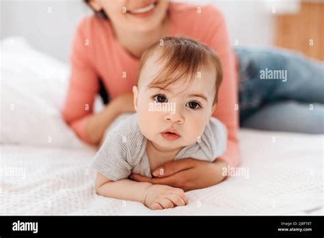 Closeup Portrait Of Cute Little Kid Mom Helping Her Crawl On Bed In