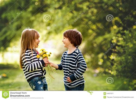 Beautiful Boy And Girl In A Park Boy Giving Flowers To