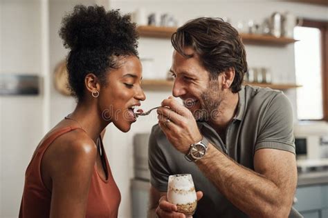 romantic happy and interracial couple eating a healthy yogurt together in a cute sweet and fun