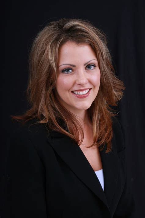 A Woman In A Black Suit Smiling At The Camera