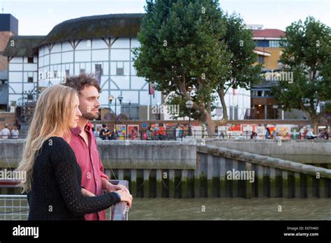 A Young Couple Standing In Front Of The Globe Theatre In London