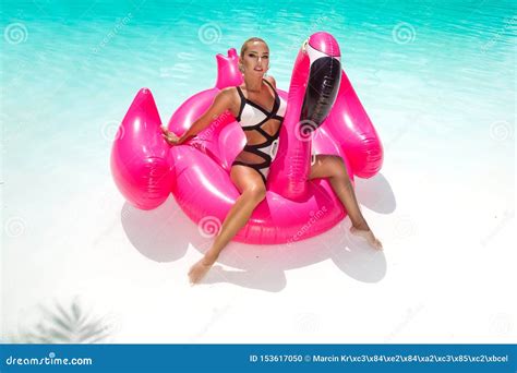 mooie sexy verbazende jonge vrouw in een zwembadzitting op het opblaasbare roze vlammen en