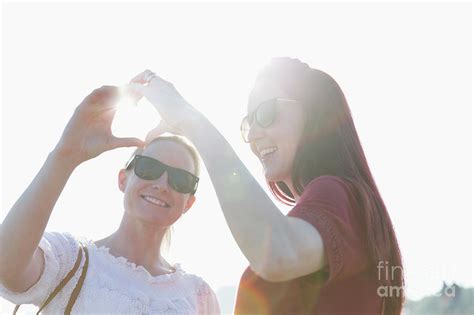 lesbian couple forming heart shape with hands photograph by caia image science photo library