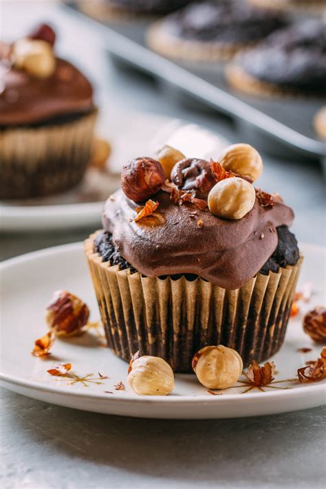 A Cupcake With Chocolate Frosting And Nuts On Top Sitting On A White Plate