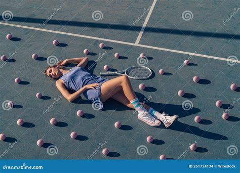 Closeup Of A Tennis Player Lying On The Sunlit Blue Tennis Court With