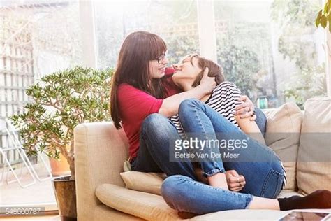 Lesbian Couple Cuddling On Sofa In Living Room
