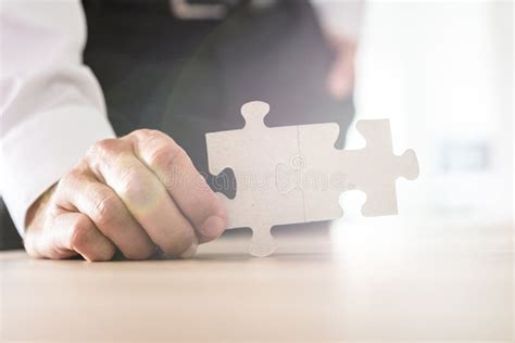 Businessman Holding Two Joined Matching Puzzle Pieces Stock Photo