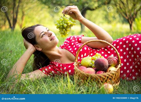 Girl With A Bunch Of Grapes Lies In The Garden Near The Fruit Basket