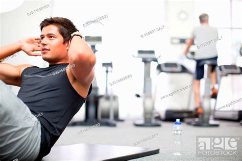 Smiling Man Doing Sit Ups In Gymnasium Stock Photo Picture And