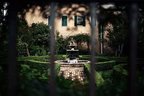 A View Through A Gate At A House With A Fountain In The Middle